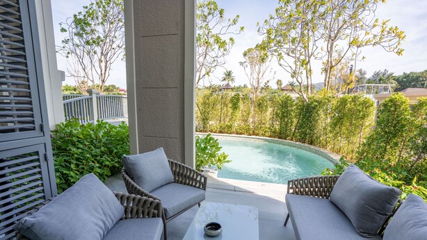 A poolside seating area with wicker furniture and a glass table, overlooking a swimming pool. - The Title Legendary 2BR Pool Access, Bang Tao, Phuket (Tambon Choeng Thale)
