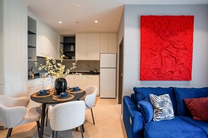 Ein moderner Wohnraum mit Essbereich, Küche und einem blauen Sofa mit roter Akzentwand.