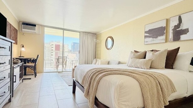 Een hotelkamer met een bed, een bureau en uitzicht op de stad.