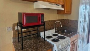Una cocina compacta con armarios de madera, microondas, estufa y lavamanos.