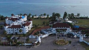 Un hotel costero con varias edificaciones, un estacionamiento y vista al océano.