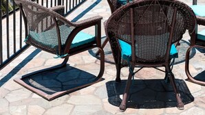Een terras aan zee met rieten meubels en uitzicht op de oceaan.