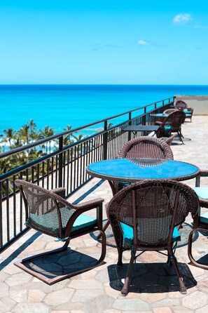 A seaside patio with wicker furniture and a view of the ocean. - Ocean View Across Waikiki Beach Modern Bungalow (Honolulu)