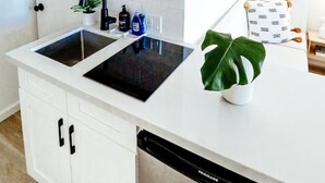Een moderne keuken met witte kastjes, een ingebouwde magnetron, een fornuis en een vaatwasser.