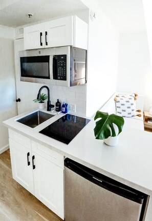 A modern kitchen with white cabinetry, a built-in microwave, a stove, and a dishwasher. - Ocean View Across Waikiki Beach Modern Bungalow (Honolulu)