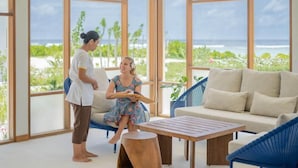A room with large windows, a sofa, a wooden table, and a chair.