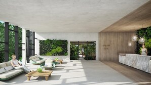A modern lobby with seating areas, a reception desk, and a wall with greenery.