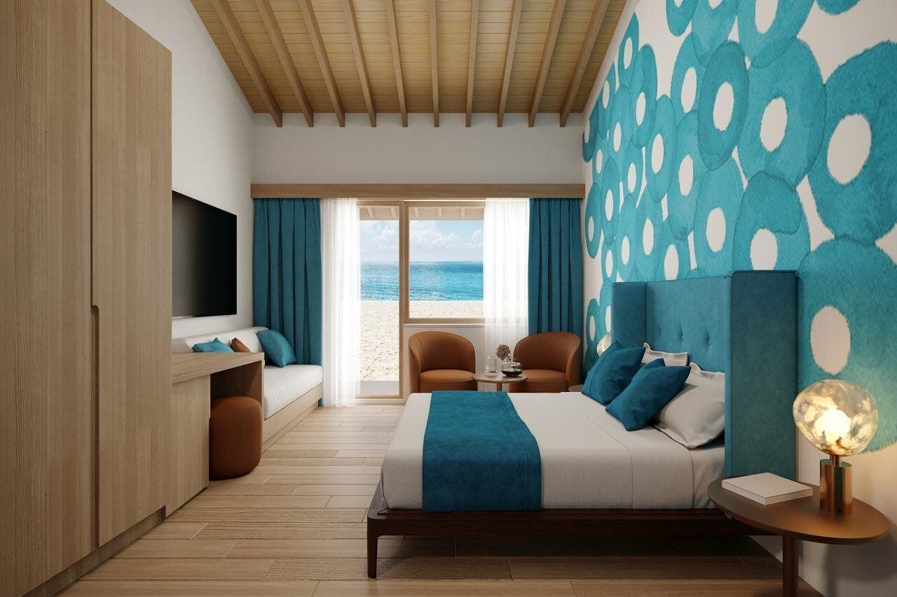 Una habitación de hotel moderna con cama, zona de estar y vistas a la playa.