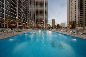 A swimming pool with lounge chairs and a high-rise building in the background. - Waikiki Gem, Stunning Ocean View, Parking Included (Honolulu)
