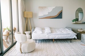 A modern bedroom with a large bed, a white armchair, a floor lamp, and a painting on the wall. - Waikiki Gem, Stunning Ocean View, Parking Included (Honolulu)