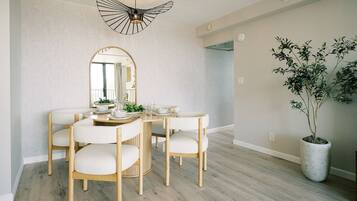 A dining area with a round table, four chairs, a large mirror, and a potted plant.