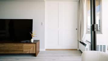 Un salon moderne avec un téléviseur à écran plat, un meuble en bois et un canapé blanc.
