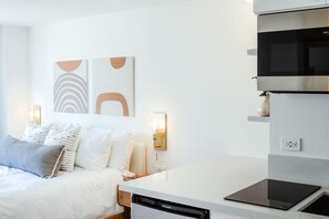 Ein modernes Schlafzimmer mit Bett, Nachttischlampen und abstrakter Wandkunst.