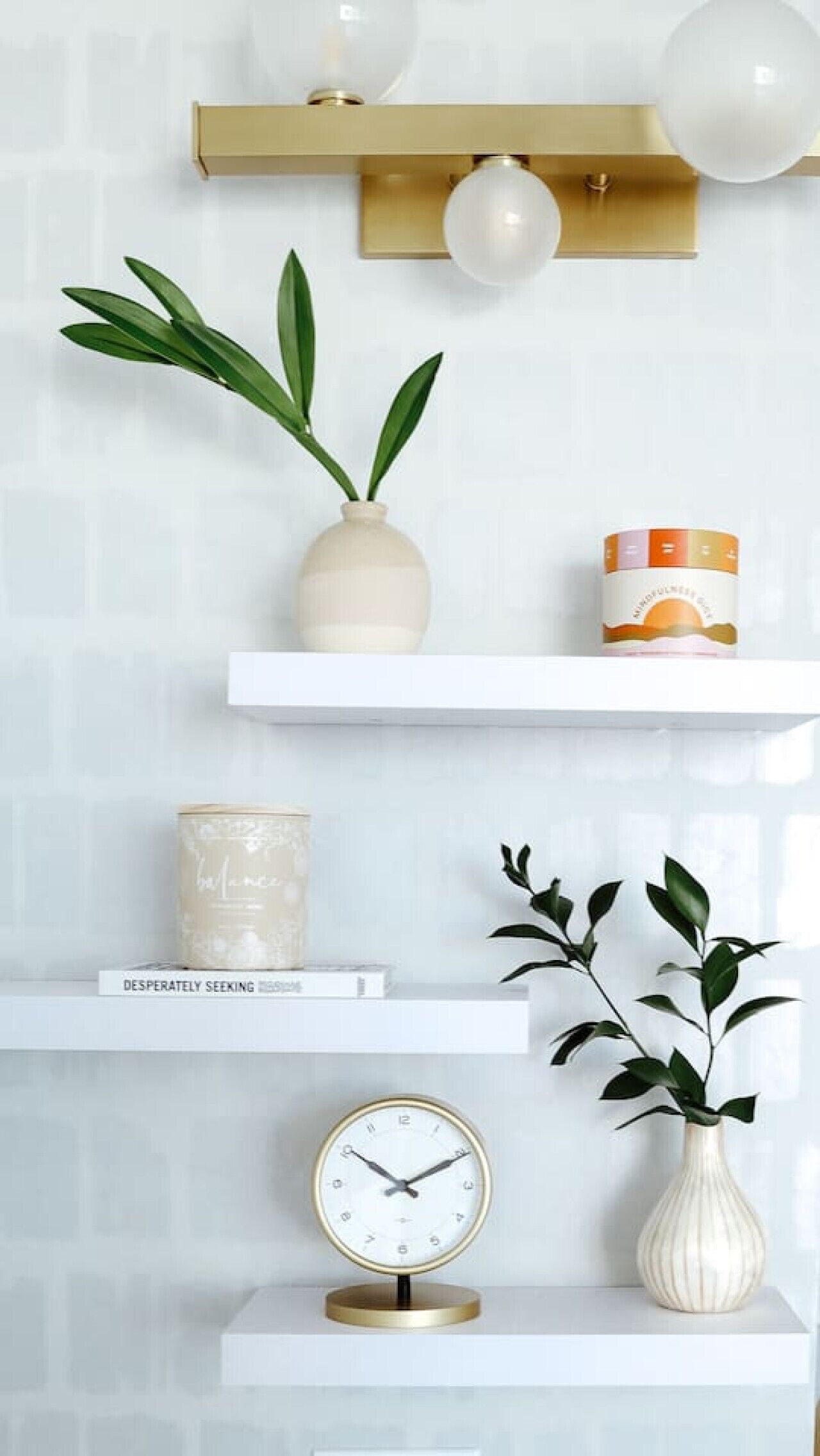 Un mur avec trois étagères blanches, chacune contenant des objets différents.