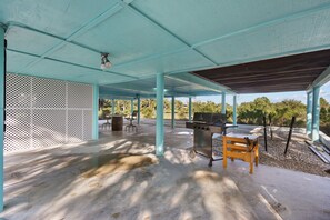 An outdoor covered patio area with a barbecue grill, seating, and a view of the surrounding landscape. - Eagle View: Waterfront Privacy with Floating Dock! (Cedar Key)