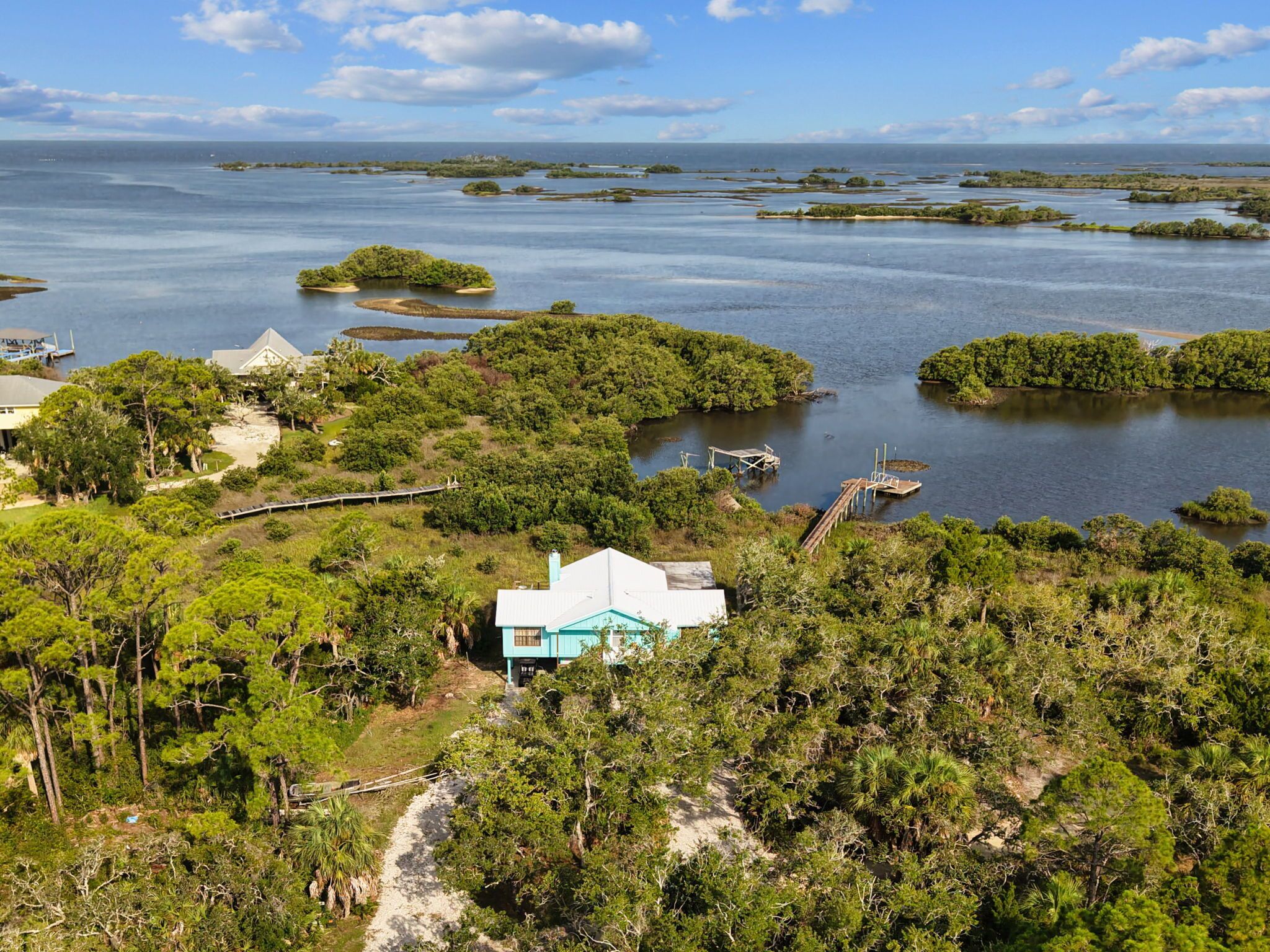 Une propriété située sur la côte, avec une maison entourée d’une végétation luxuriante et plusieurs petites îles dans l’eau.