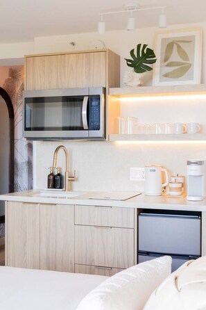 A compact kitchenette with a microwave, sink, and coffee maker. - Ocean Breeze Bungalow Across Waikiki Beach (Honolulu)