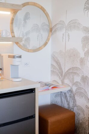 A room with a coffee maker, a mirror, a bookshelf, and a patterned wall. - Ocean Breeze Bungalow Across Waikiki Beach (Honolulu)