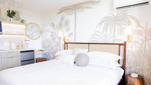 Ein Hotelzimmer mit Bett, Nachttischen, Schreibtisch und einer Küchenzeile.