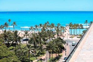 A coastal view with a beach, palm trees, and a clear blue sky. - Ocean Breeze Bungalow Across Waikiki Beach (Honolulu)