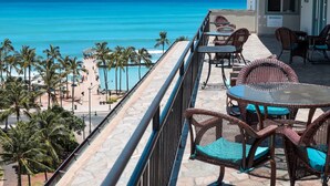 Ein Balkon mit Korbmöbeln mit Blick auf Strand und Meer.