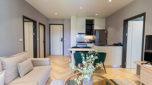 A modern living room with a sofa, a coffee table, and a dining area with chairs. - The Title Legendary 2BR, 5 Min to Bang Tao Beach (Tambon Choeng Thale)