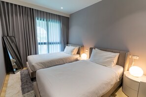 Ein Hotelzimmer mit zwei Betten, einem großen Fenster mit Vorhängen, einem Flachbildfernseher und Nachttischlampen.