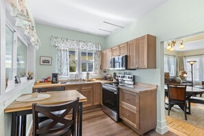 A compact kitchen with wooden cabinets, a microwave, and a stove. - Two Waterfront Cottages in Cedar Key Amazing View! (Cedar Key)