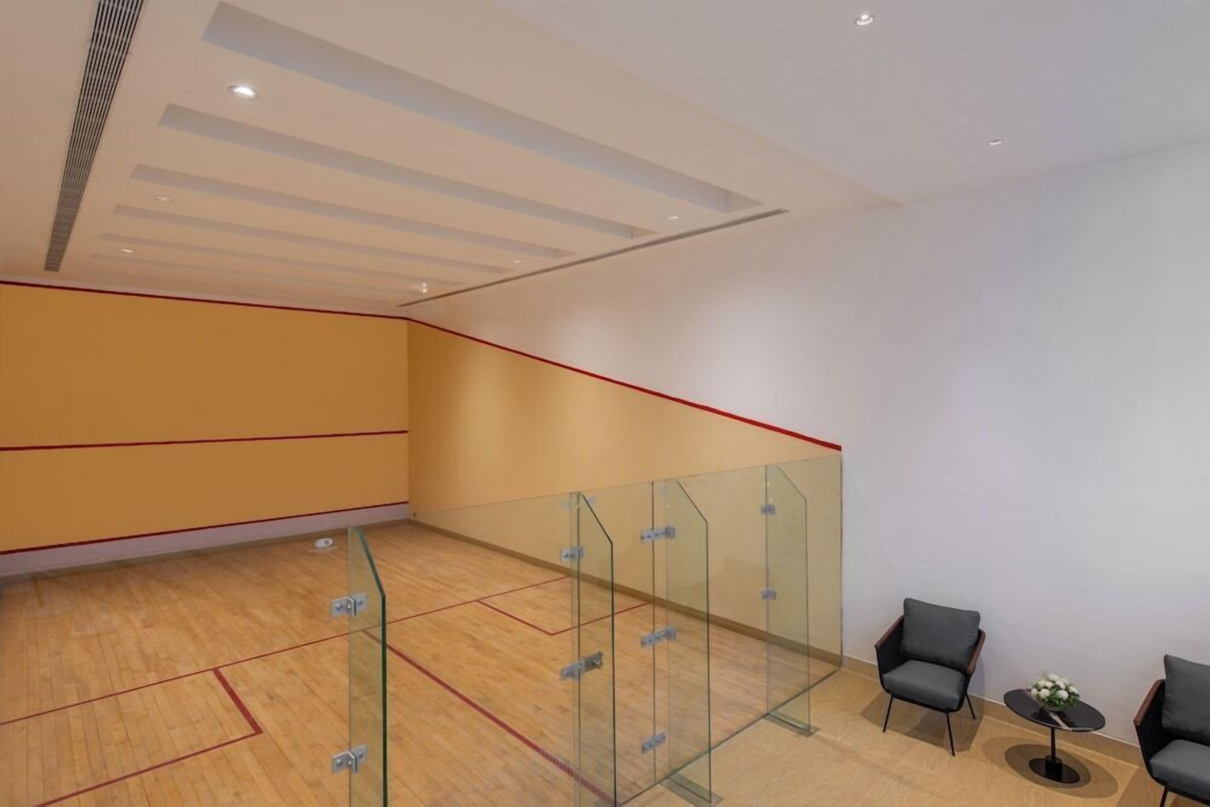 A spacious indoor area with a wooden floor, glass partitions, and seating arrangements.