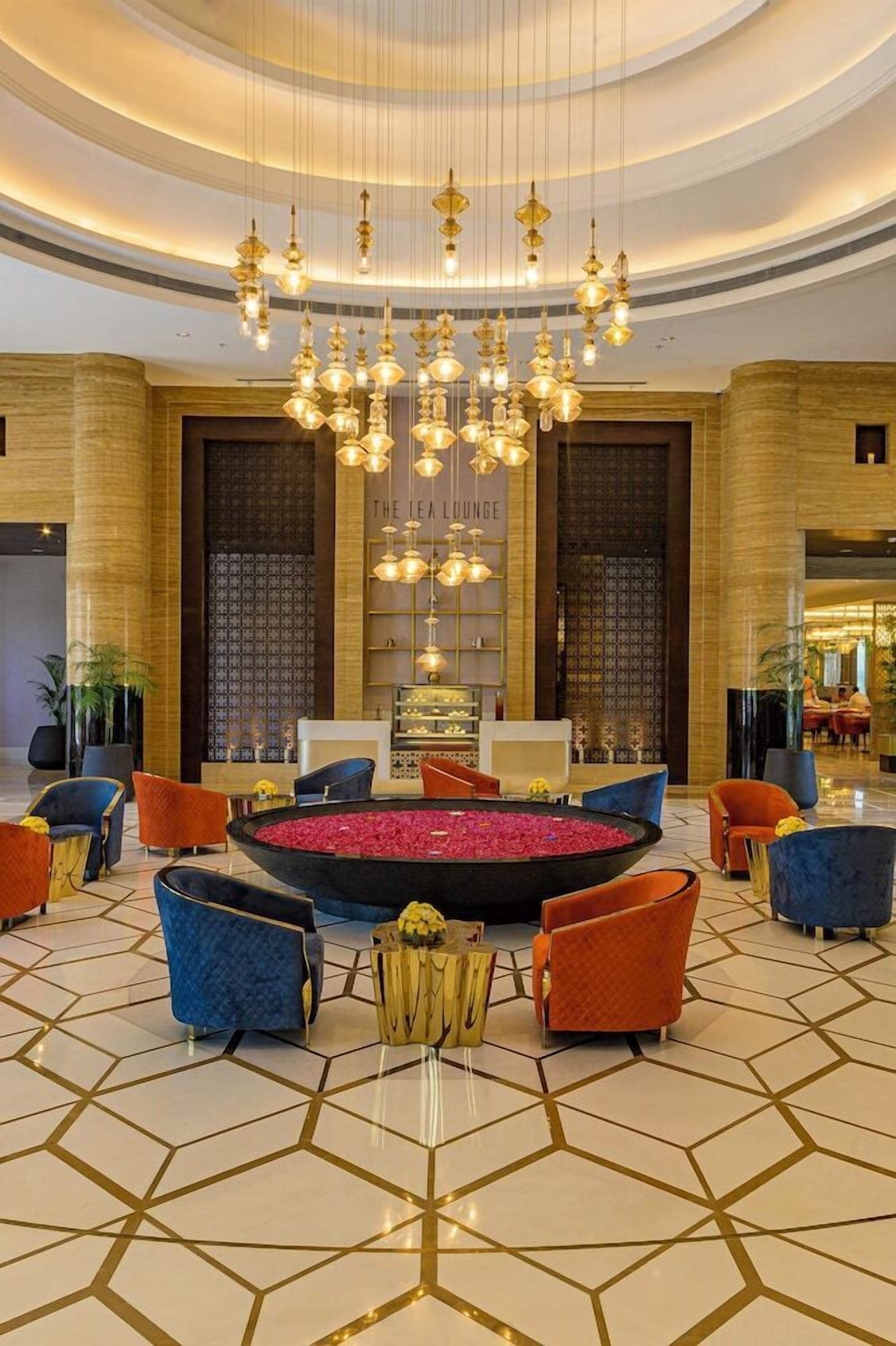 A lobby with a central seating area, a chandelier, and a patterned floor.
