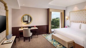 Camera d'albergo con un letto, una scrivania, una sedia, un televisore e un'ampia finestra vista.