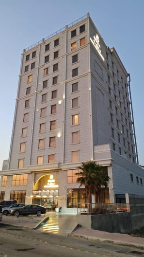 A multi-story hotel with a prominent entrance and a parking area in front. - Enala Hotel EL Khobar (Al Khobar)