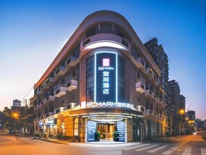 A hotel with a curved facade, illuminated signage, and a modern entrance. - Echarm Hotel (Shanghai)