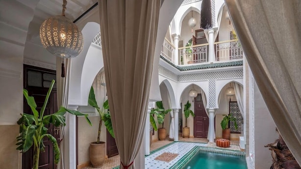 A courtyard with a pool, potted plants, and a hanging light fixture. - Riad Bab el Qamar (Marrakech)