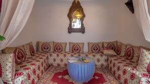 A room with a patterned sofa set, a decorative hanging light fixture, and a patterned rug. - Riad Bab el Qamar (Marrakech)