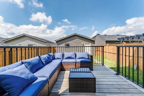A wooden deck with a sectional sofa and a coffee table. - Stylish 3BR Home With A/C | Fast Wifi | Garage Parking | Sleeps 10 (Calgary)