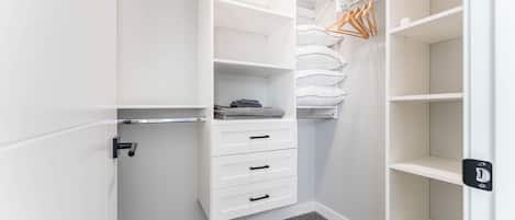 A walk-in closet with open shelves, a hanging rod, and a door with a lock.