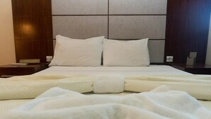 A neatly made bed with white bedding and pillows, a wooden headboard, and a bedside table with a lamp.