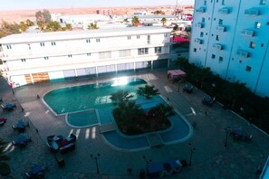 A hotel with a swimming pool, outdoor seating, and a view of the surrounding area. - Residence Anis (Hassi Messaoud)