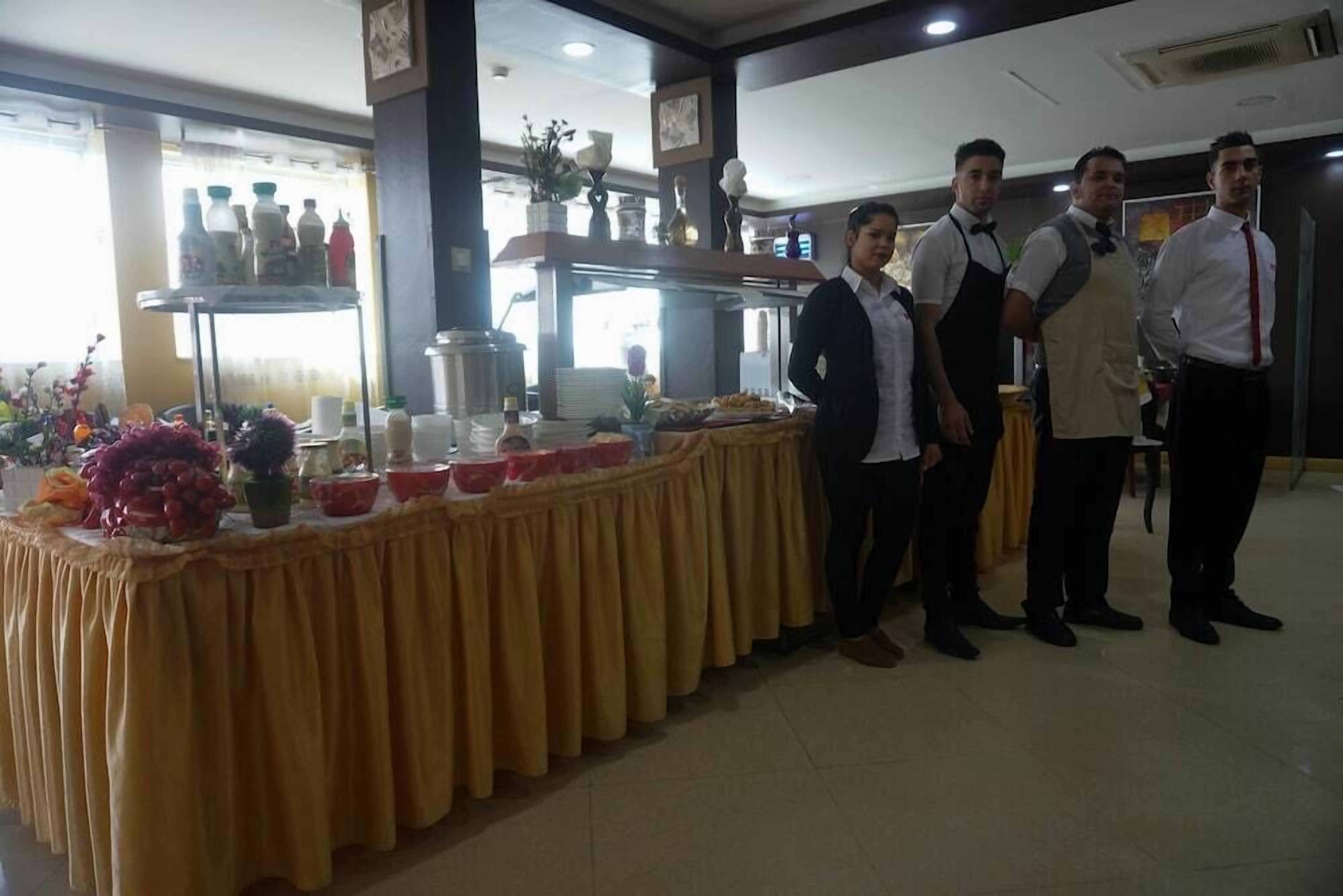 A buffet setup with a yellow tablecloth, food items, and a beverage station.