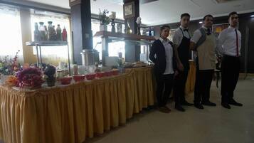 A buffet setup with a yellow tablecloth, food items, and a beverage station.