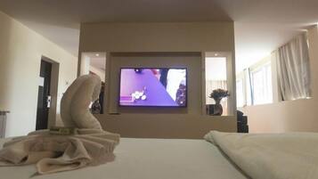 A hotel room with a bed, a television mounted on the wall, and a window with curtains.