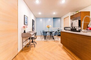 A modern kitchen with a dining area, wooden flooring, and a view through a window with blue-tinted glass. - Roma Norte Penthouse, Rooftop & Skyline Views (Mexico City)
