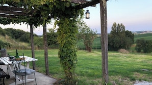 A covered outdoor seating area with a table and chairs, surrounded by greenery and a view of the countryside. - Traditional 19th century stone farmhouse sympathetically restored with views. (Saint-Martial-Viveyrol)