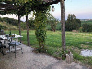 A covered outdoor seating area with a table and chairs, surrounded by greenery and a view of the countryside. - Traditional 19th century stone farmhouse sympathetically restored with views. (Saint-Martial-Viveyrol)
