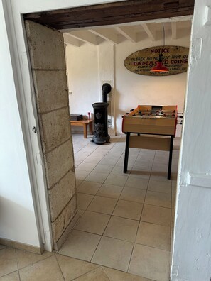 A room with a foosball table, a vintage stove, and a notice on the wall. - Traditional 19th century stone farmhouse sympathetically restored with views. (Saint-Martial-Viveyrol)