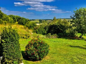 A lush green landscape with a variety of trees and shrubs, a clear blue sky, and a distant view of rolling hills. - Traditional 19th century stone farmhouse sympathetically restored with views. (Saint-Martial-Viveyrol)