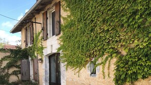 A building with a garden hose on the ground, a door, and a window with shutters. - Traditional 19th century stone farmhouse sympathetically restored with views. (Saint-Martial-Viveyrol)