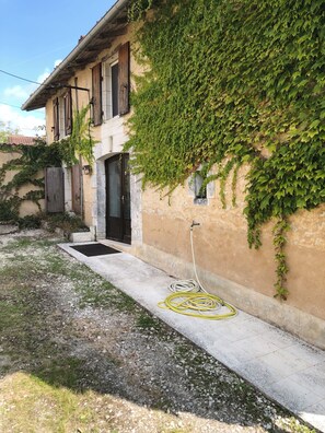 A building with a garden hose on the ground, a door, and a window with shutters. - Traditional 19th century stone farmhouse sympathetically restored with views. (Saint-Martial-Viveyrol)