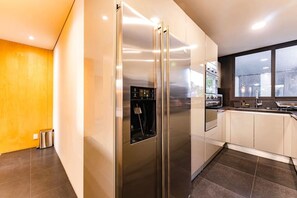 A modern kitchen with a stainless steel refrigerator, a built-in oven, and a window with a view. - Polanco Penthouse: Rooftop Swing & City Views (Mexico City)